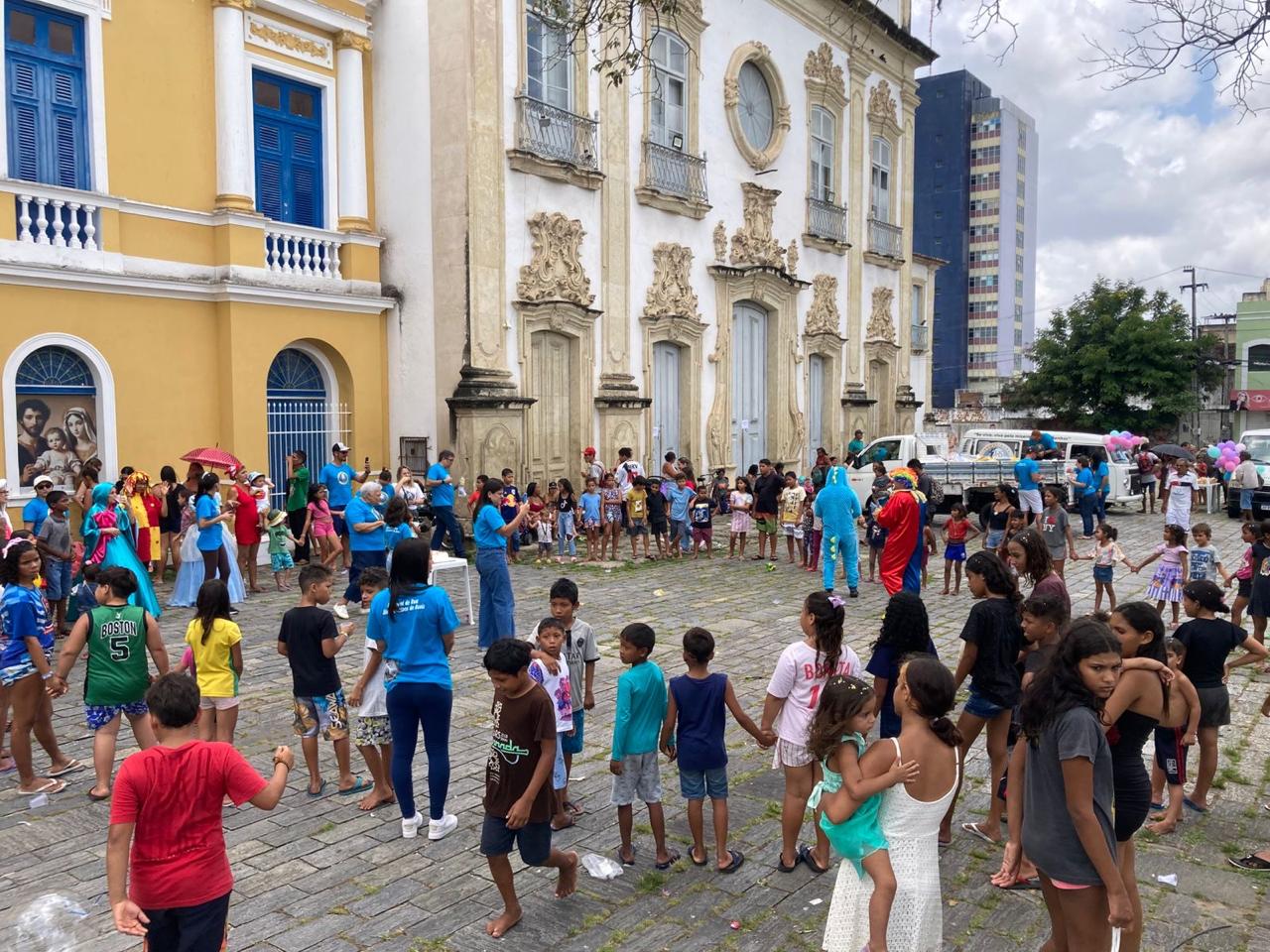 Ação comunitária da Pastoral de Rua em espaço aberto, com voluntários e famílias reunidos.